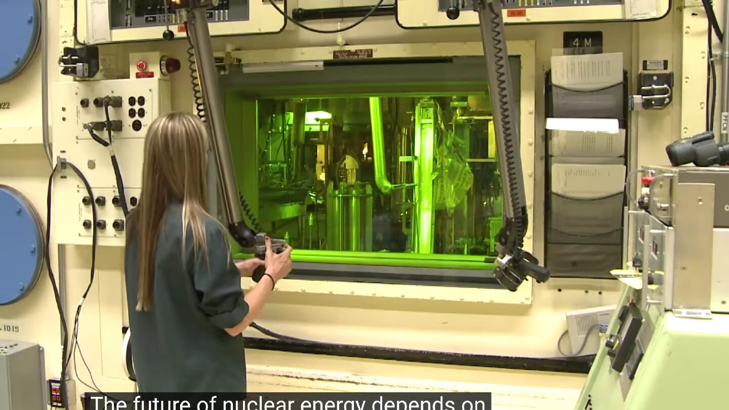 a technician at Oak Ridge National Laboratory using manipulator arms to work inside a shielded hot cell